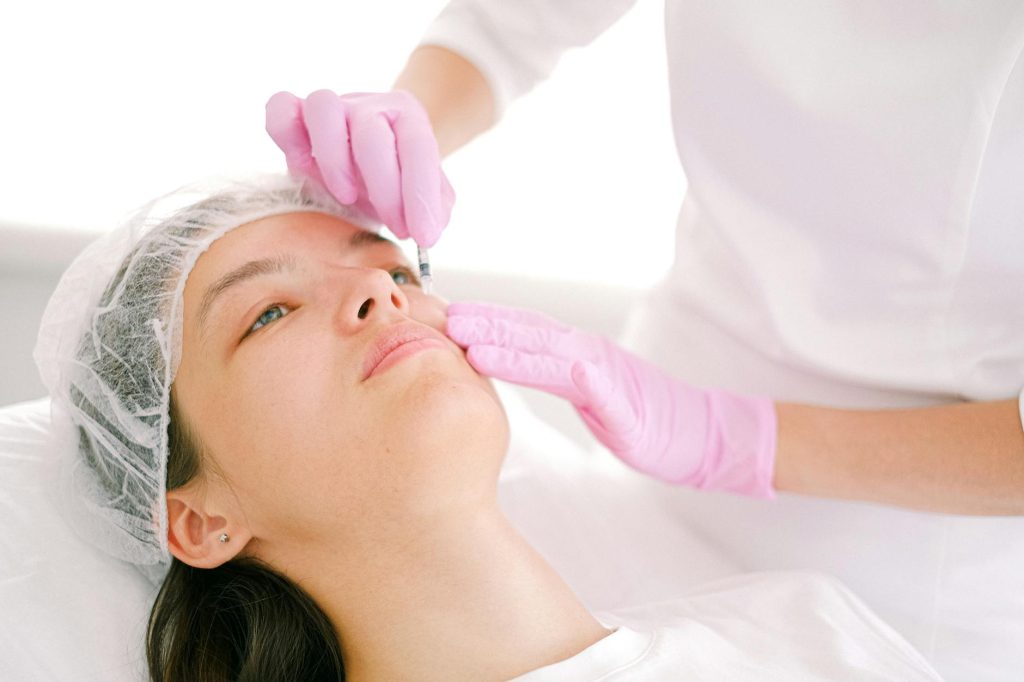 cosmetologist injecting a woman in a face with a syringe
